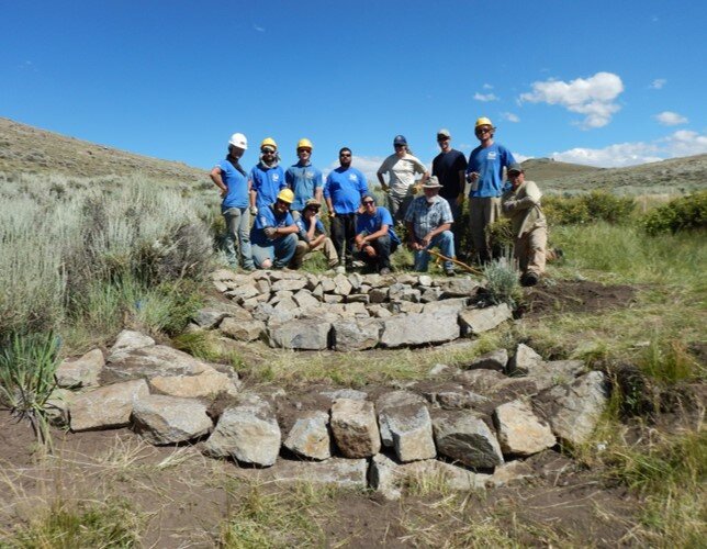 A group of people stand behind a Zeedyk structure, and example of a low-tech practice that participants learned during this technical transfer effort.