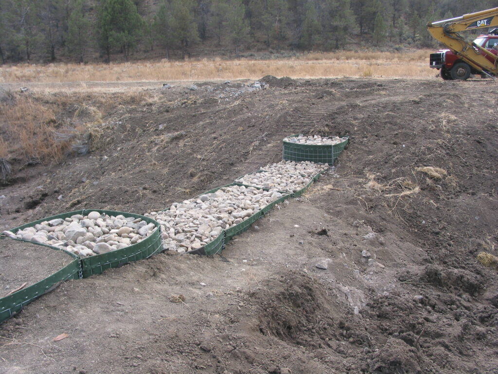 Dirt surrounds green boxes filled with rocks.