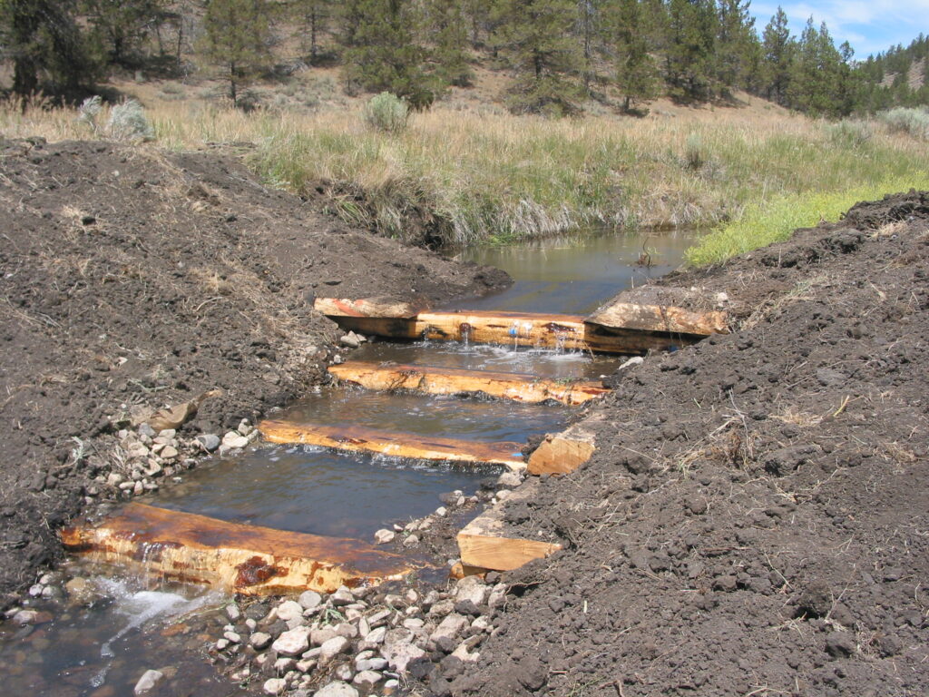 Log structures stair-step down a creek.
