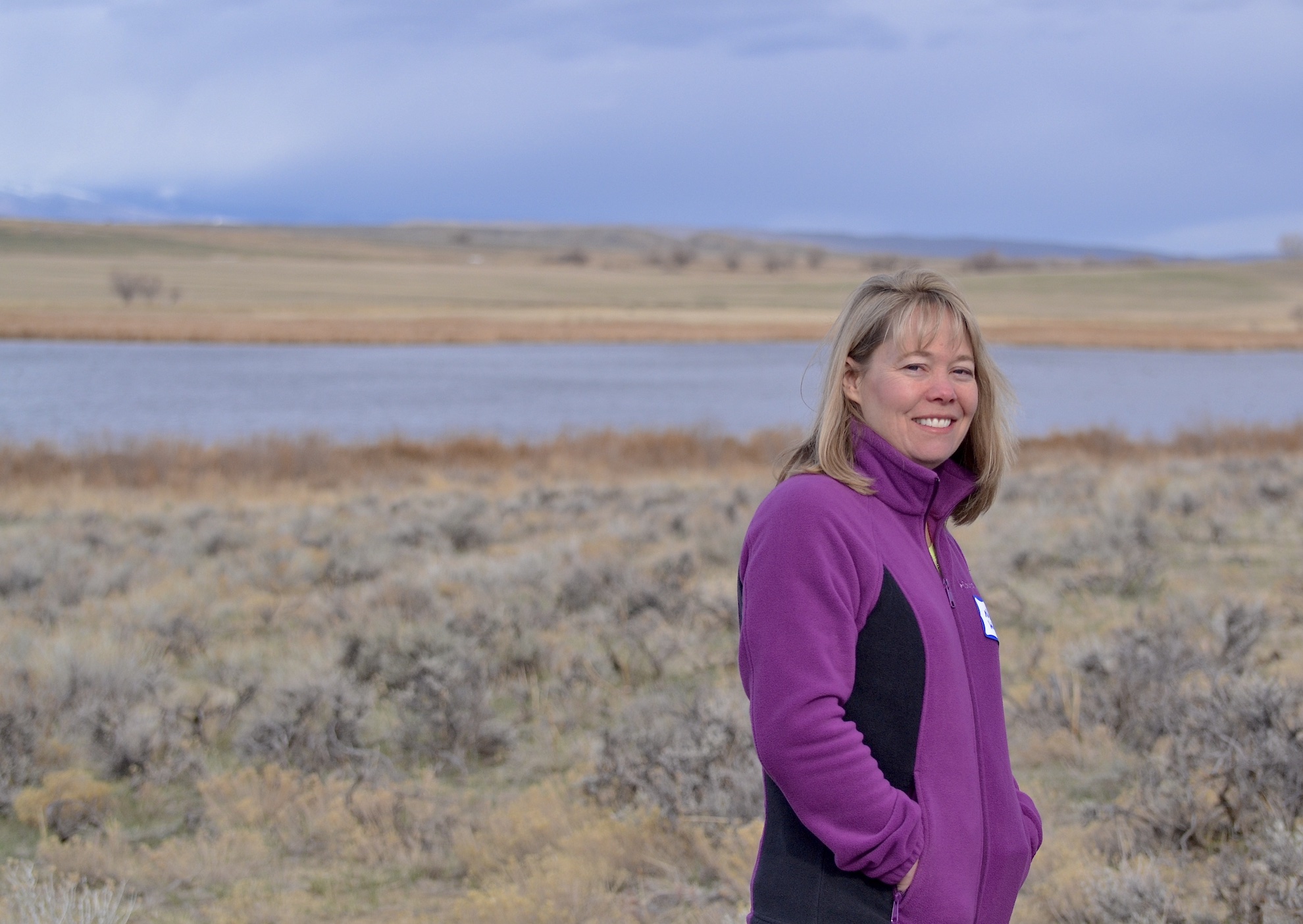 A photo of Noreen Walsh by a wetland area in the sagebrush.