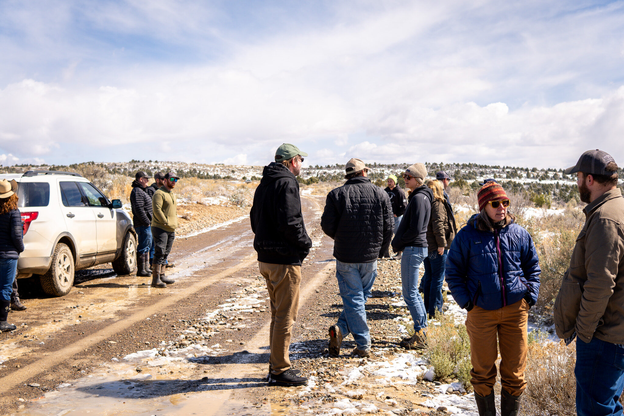 Image of partners conversing while standing in a road alongside pinyon-juniper woodlands. The image signifies partnership and networking.