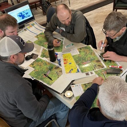 A group of people around a map draw polygons for prioritization during a technical transfer workshop